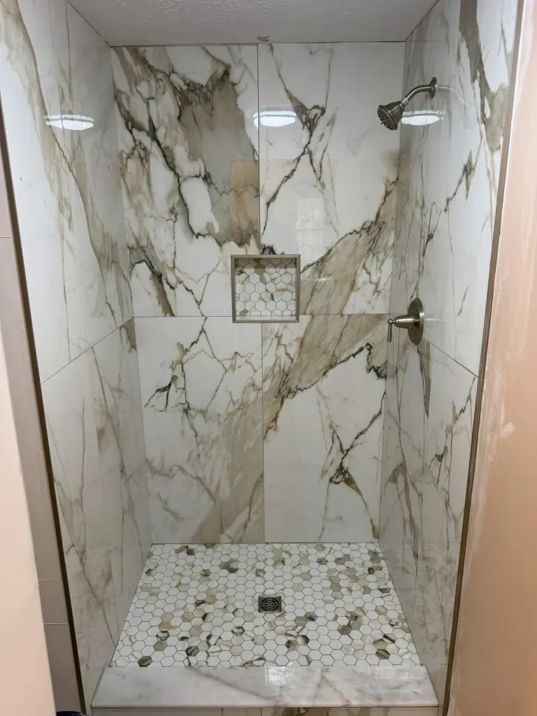 Marble-look shower with pebble floor & built-in niche