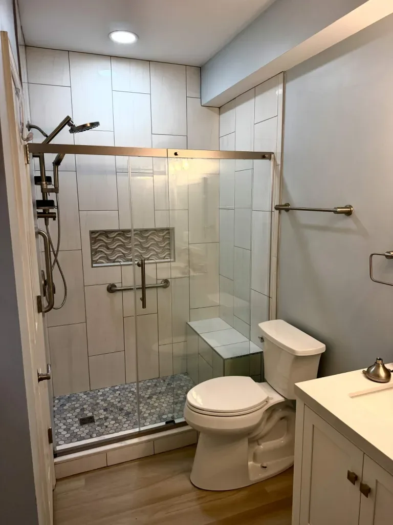 Walk-in shower with sliding glass door, bench & grab bars
